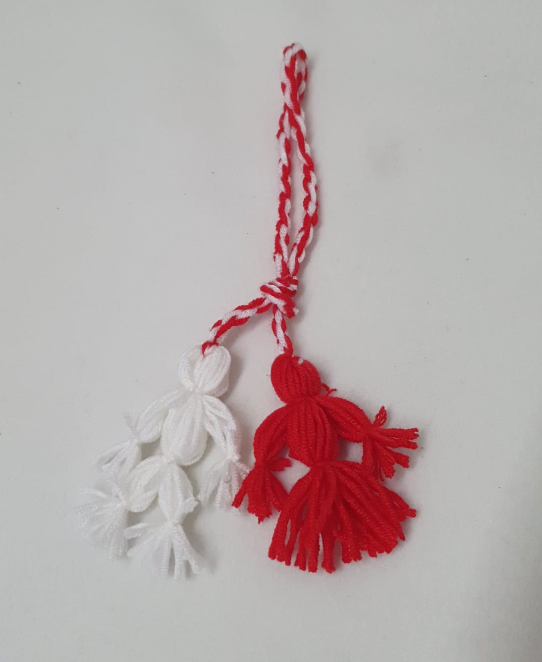 Fată și băiat, moșternire culturală, lucrați din fir acrilic în culorile roșu și alb Fată și băiat, moșternire culturală, lucrați din fir acrilic în culorile roșu și alb